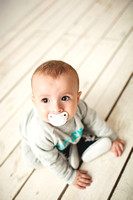 One year old cute baby boy sitting on wooden floor
